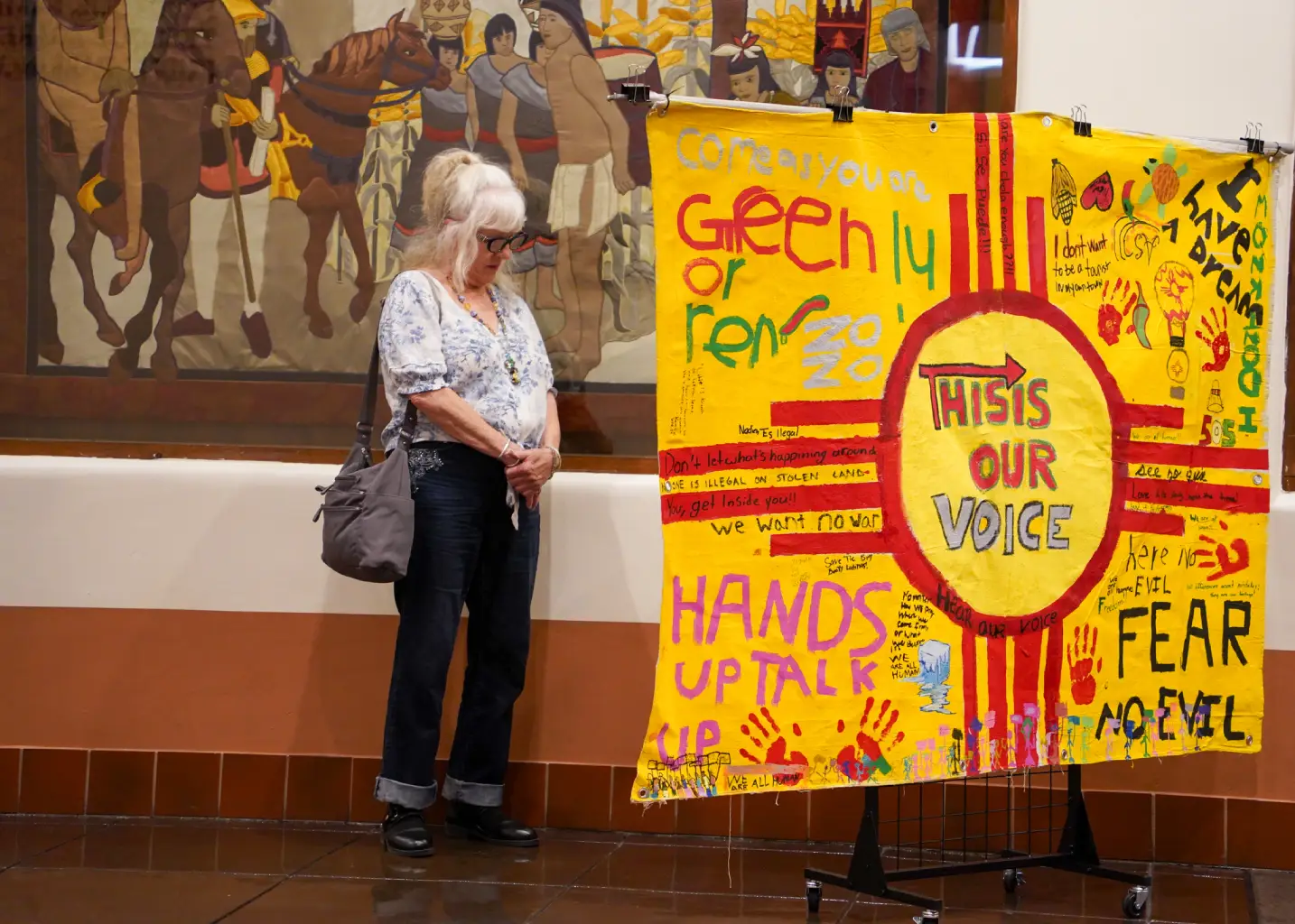 A woman pauses to view and appreciate student artwork on display